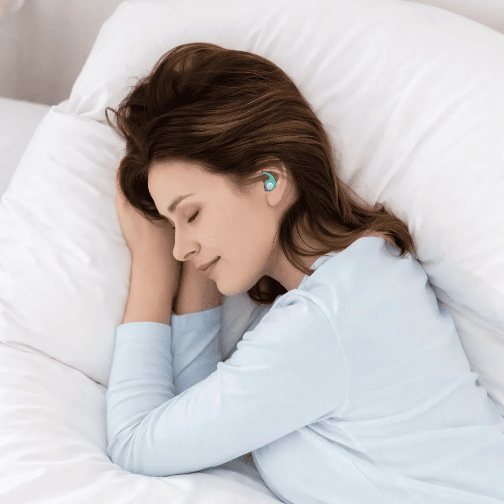 Woman sleeping with earplugs in a white bedroom