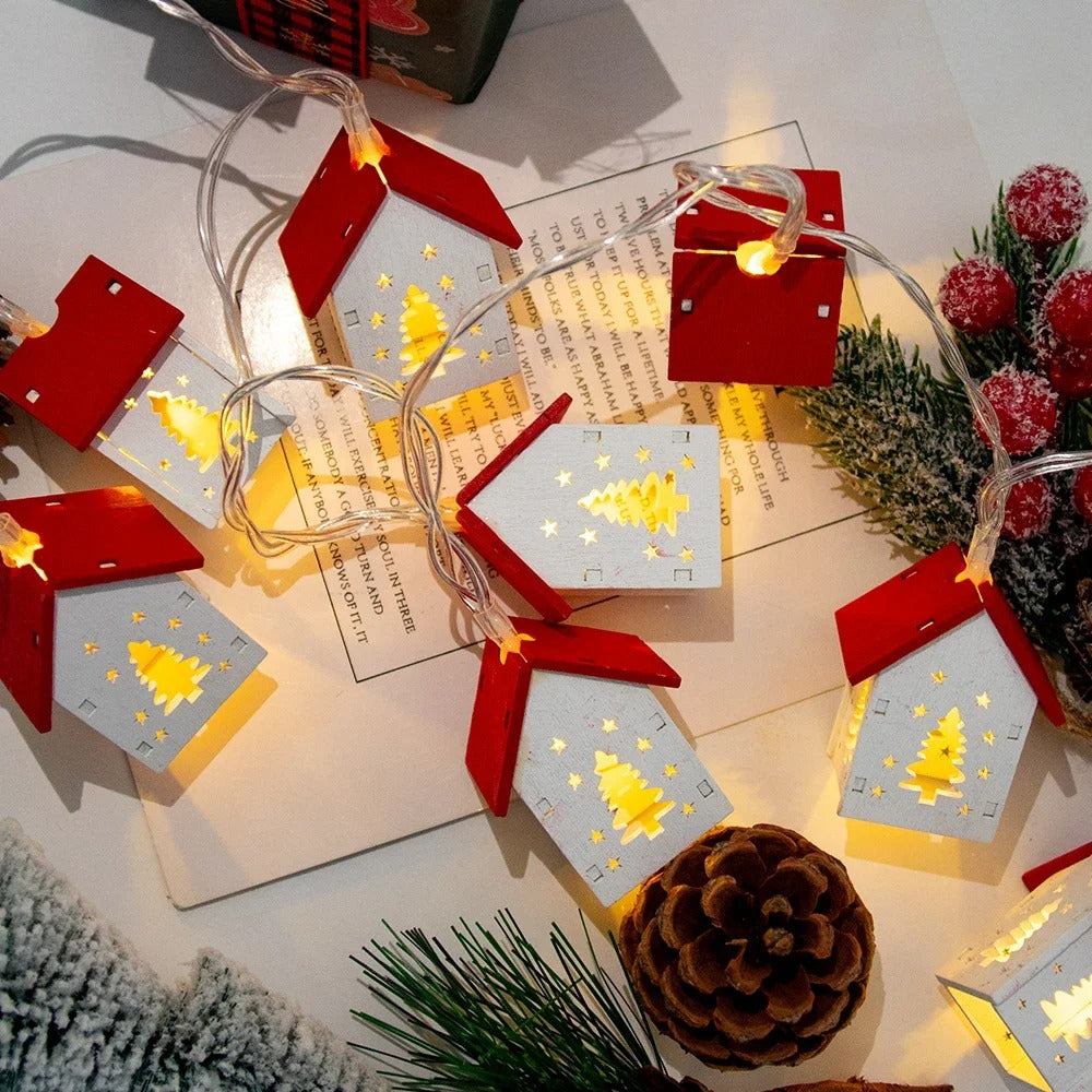 Decorative Christmas lights shaped like houses on a table with festive decorations.